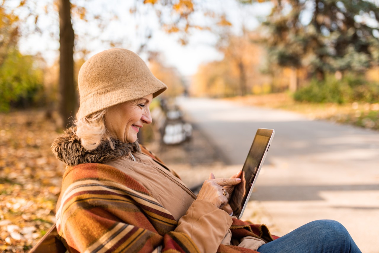 A woman seated in a park reading on her ipad
