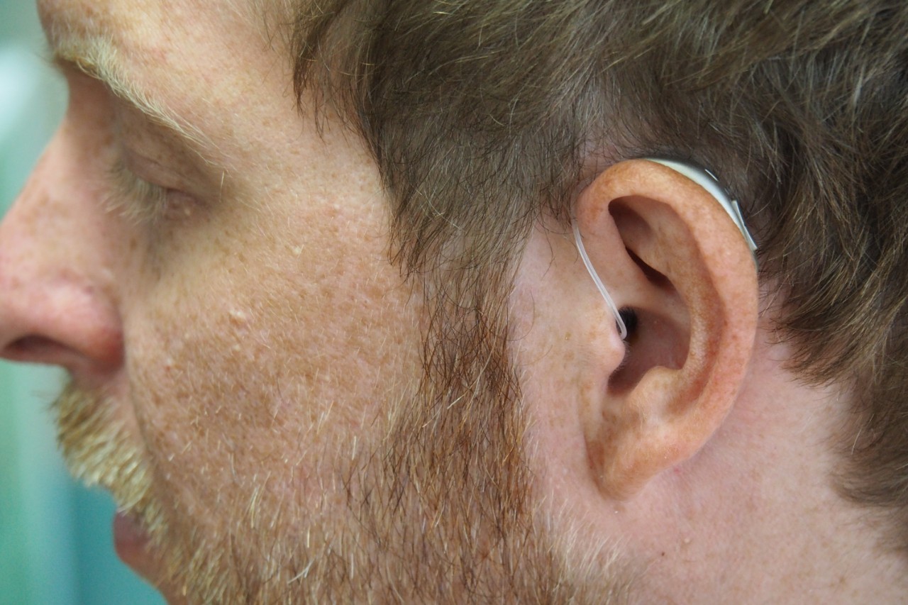 Profile of a man wearing behind the ear hearing aids