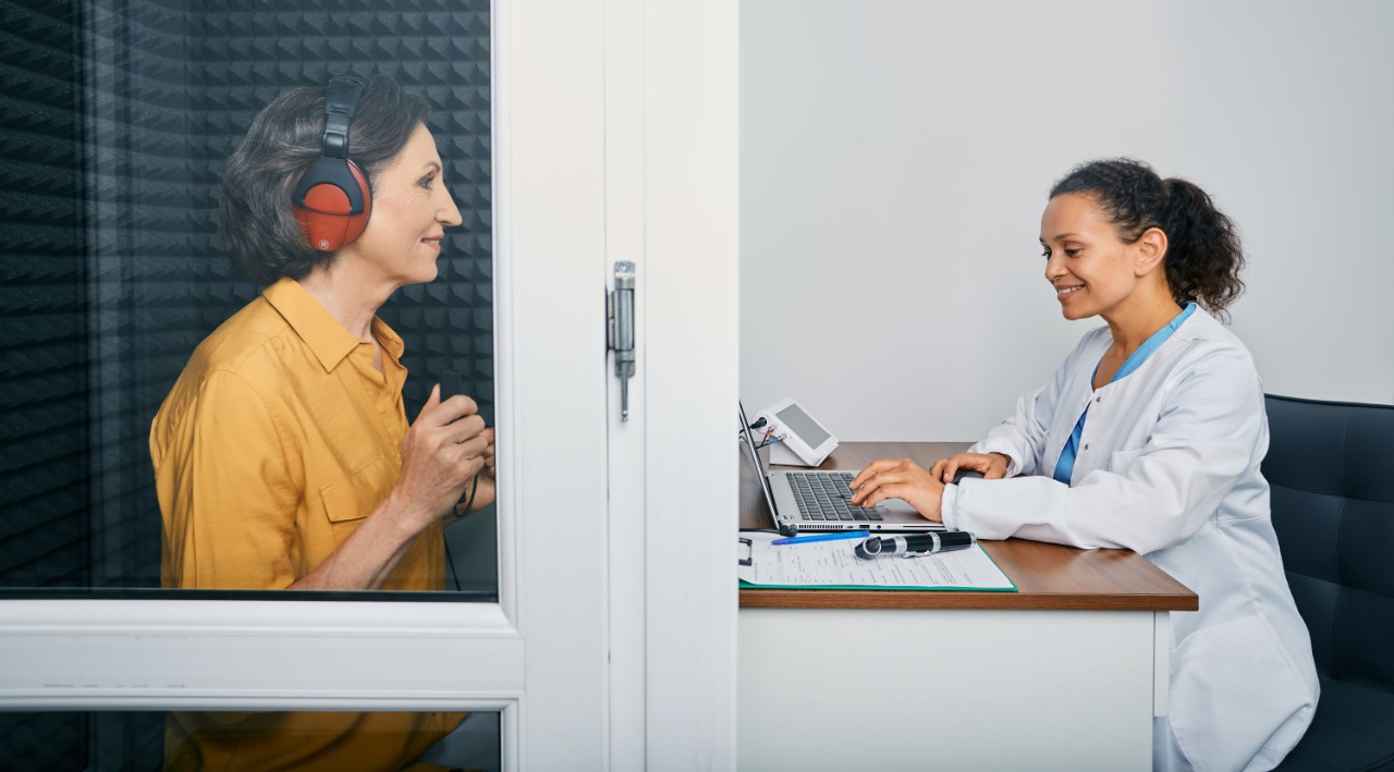 an audiologist taking a hearing exam to a woman