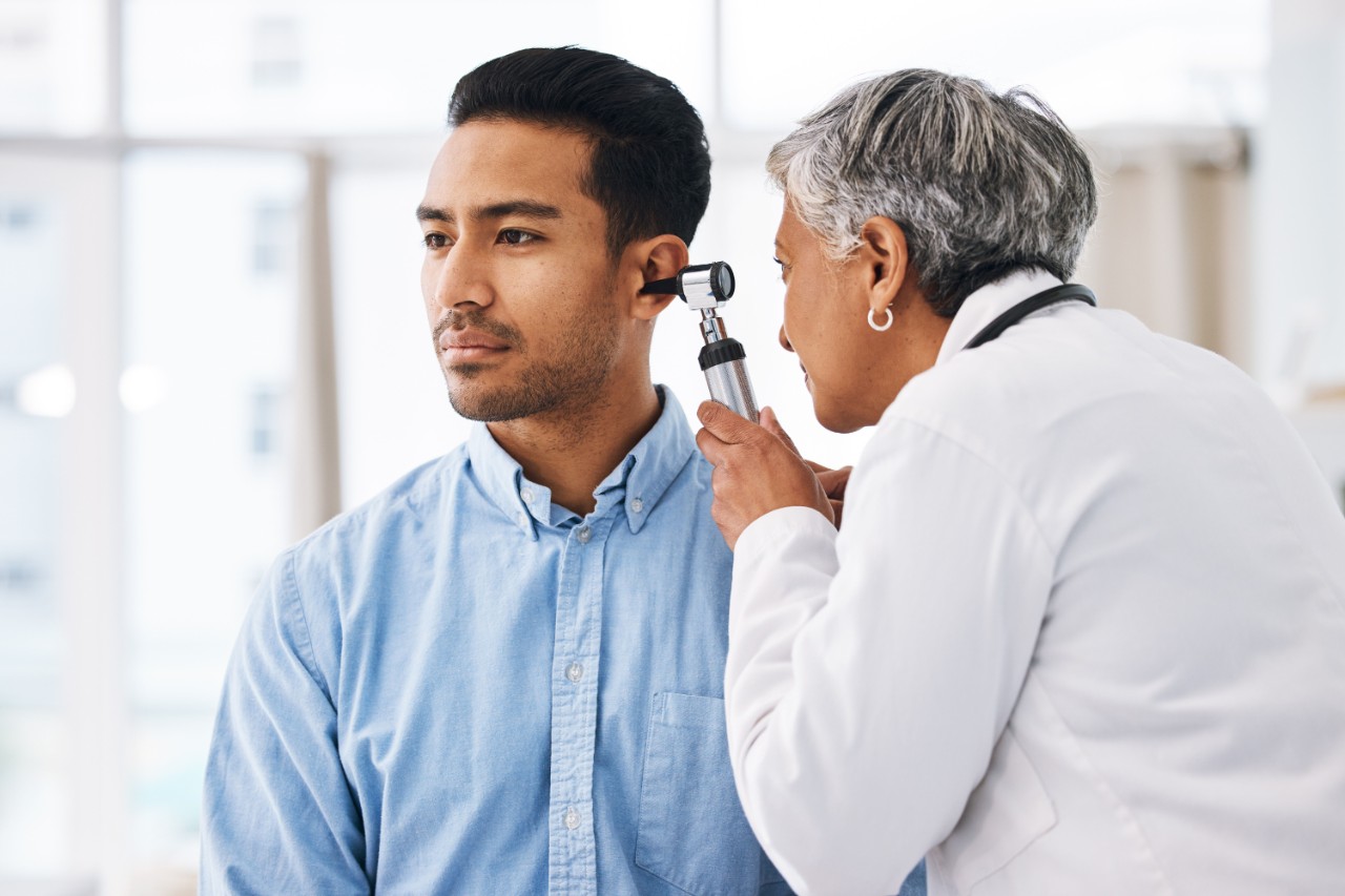 Audiólogo observando el oído de un paciente con un otoscopio