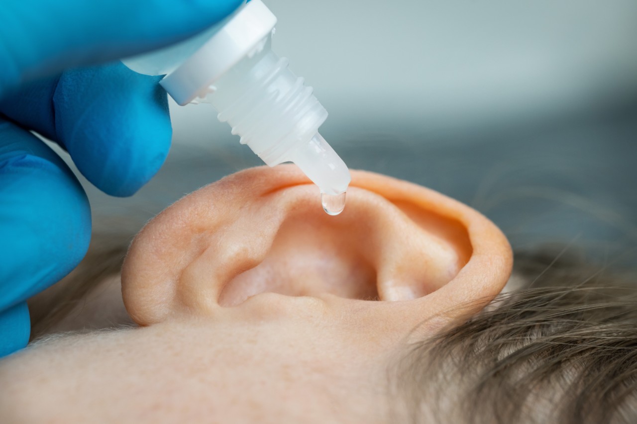 Ein Arzt gibt Ohrentropfen in das Ohr einer Patientin