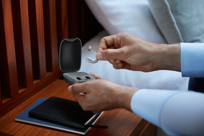 a person holding a hearing aid and its case