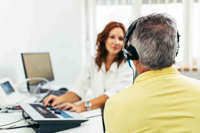 an audiologist taking a hearing exam to a man