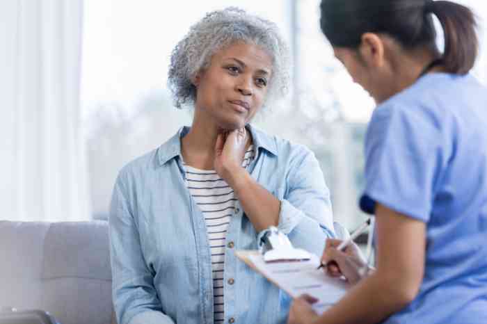 A patient holding her neck while the doctor takes notes