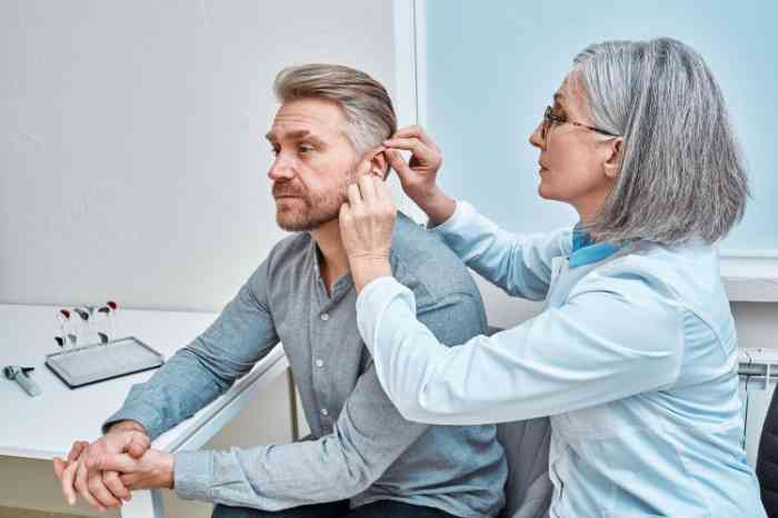 an audioprothesist helping a man wearing the hearing aid