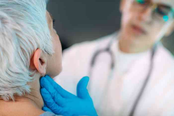 Mano de un médico evaluando el bulto detrás de la oreja de un paciente
