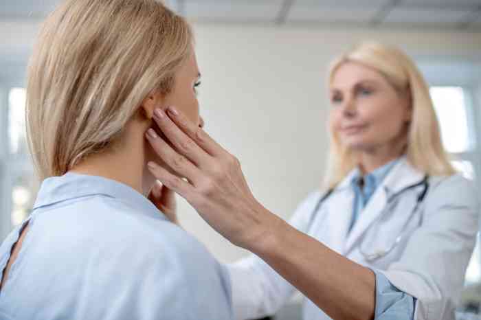 Un medico visita una donna che ha un linfonodo dietro l'orecchio