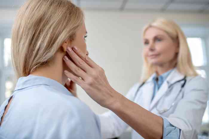Doctora buscando ganglios detrás de la oreja de una paciente