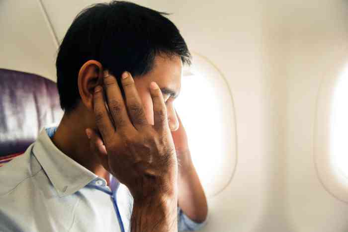 Ein Mann leidet unter Ohrenschmerzen im Flugzeug