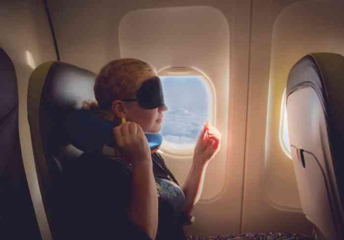 mujer en avión con almohada y antifaz.