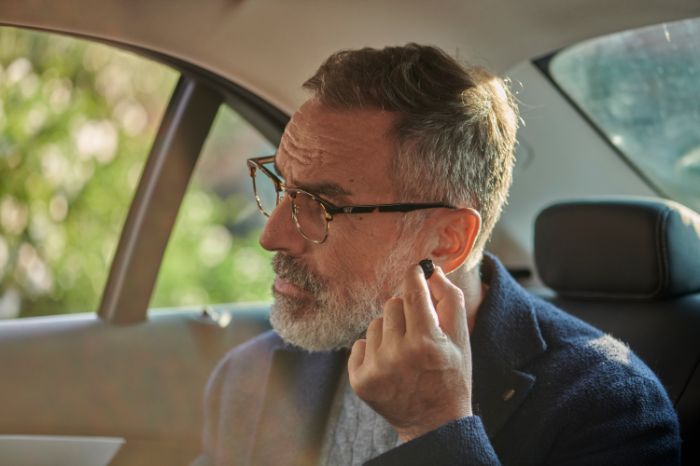 Ein Mann trägt ein Hörgerät im Auto