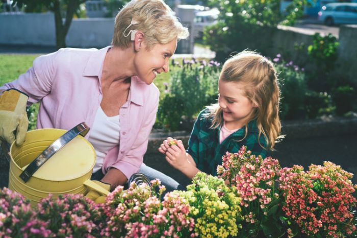 a woman with cochlear implant gardening with a little girl