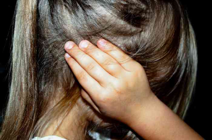 Young girl covering her ear with her hand because of the pain