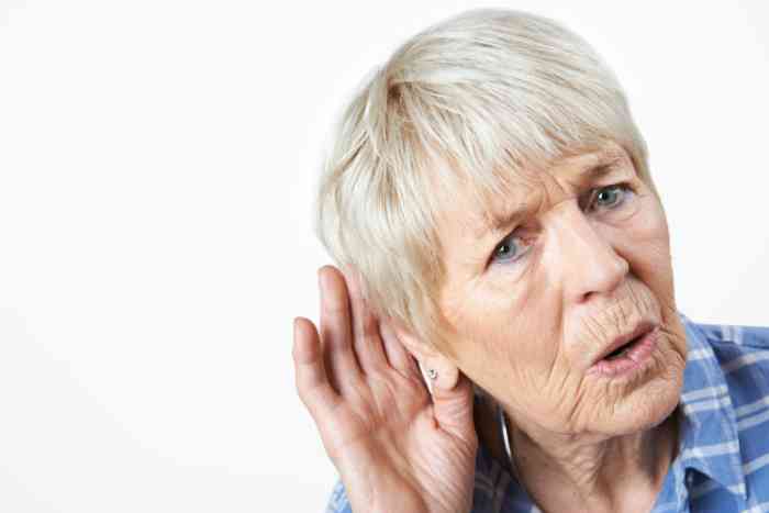 A woman with a hand close to the ear trying to listen to something