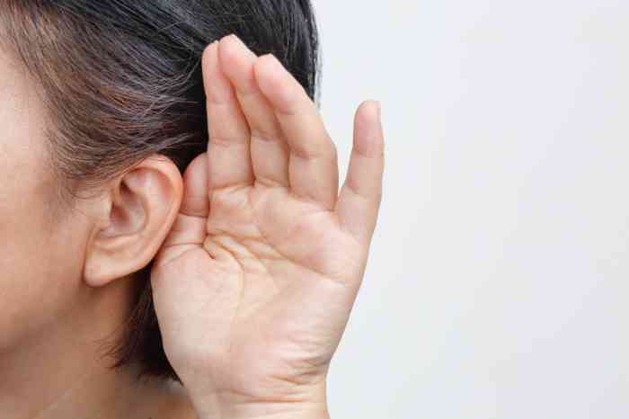 A woman with a hand close to the ear trying to listen to something