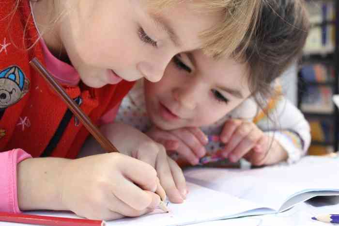 Zwei kleine Mädchen schreiben in ein Schulheft