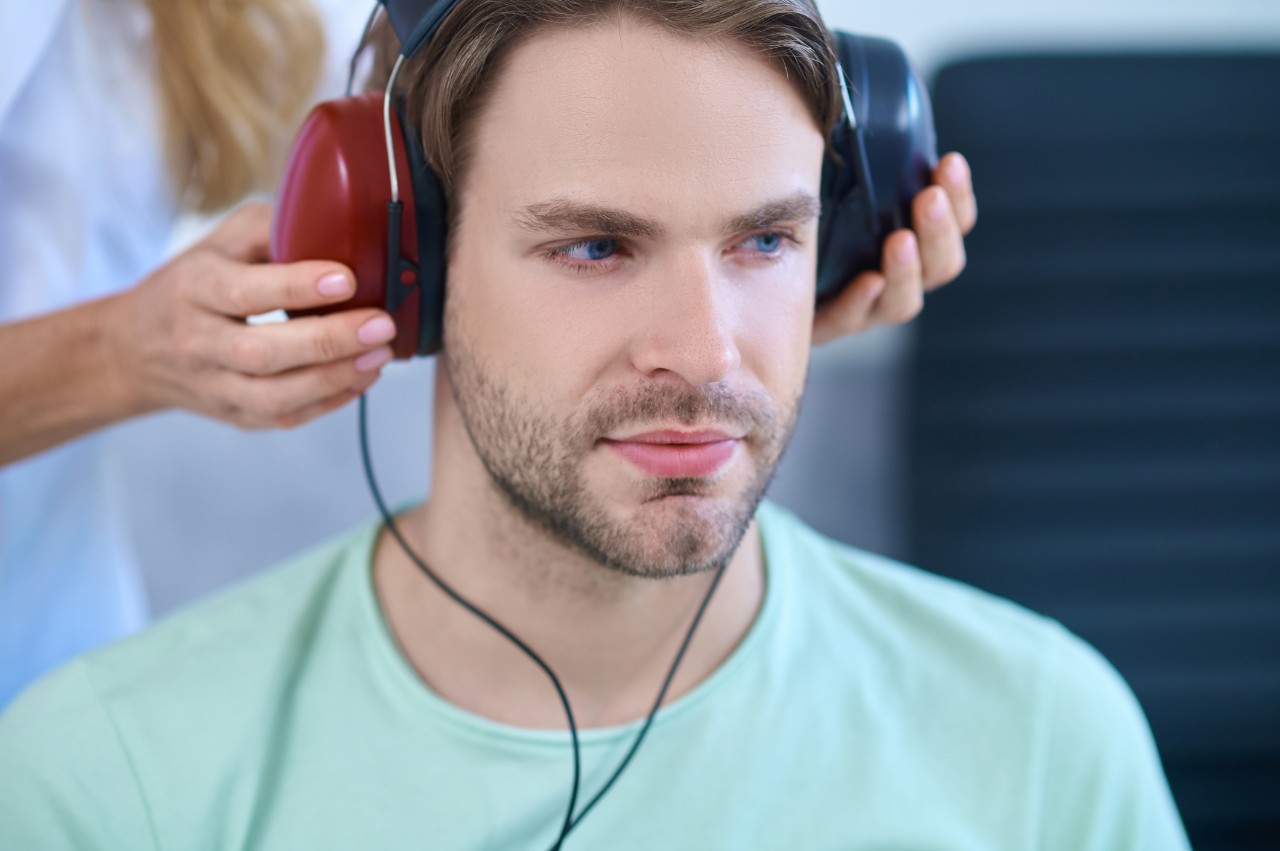 A man with a light blue shirt perfoming a hearing test