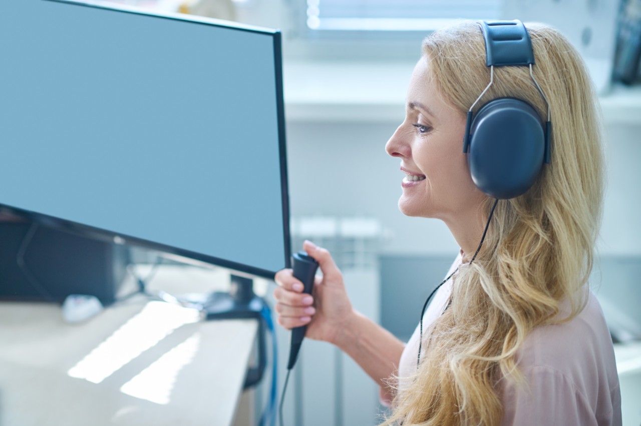 Profile of a blond woman perfoming a hearing test