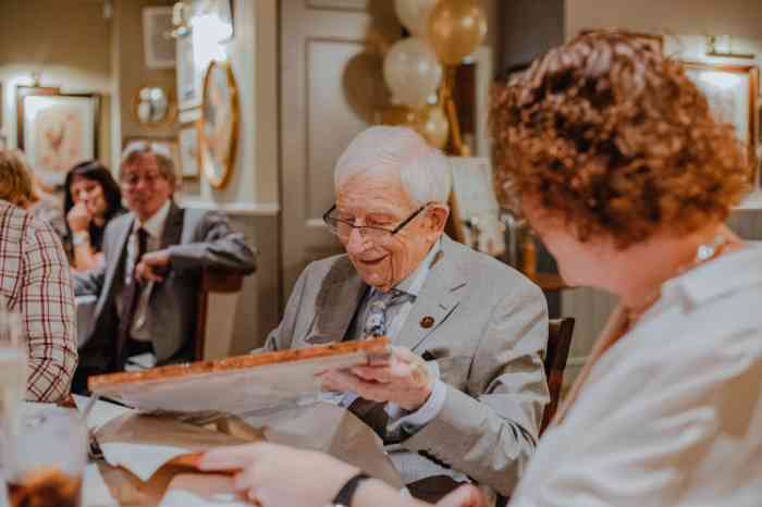 Elderly man unboxing his present at dinner table while smiling