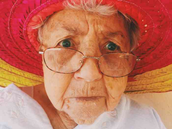 Close up of a elderly woman with glasses and red hat