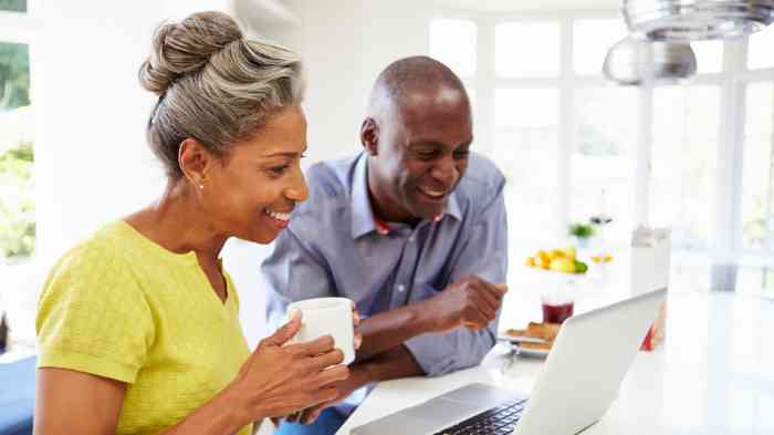 Pareja sonriendo mientras mira una computadora