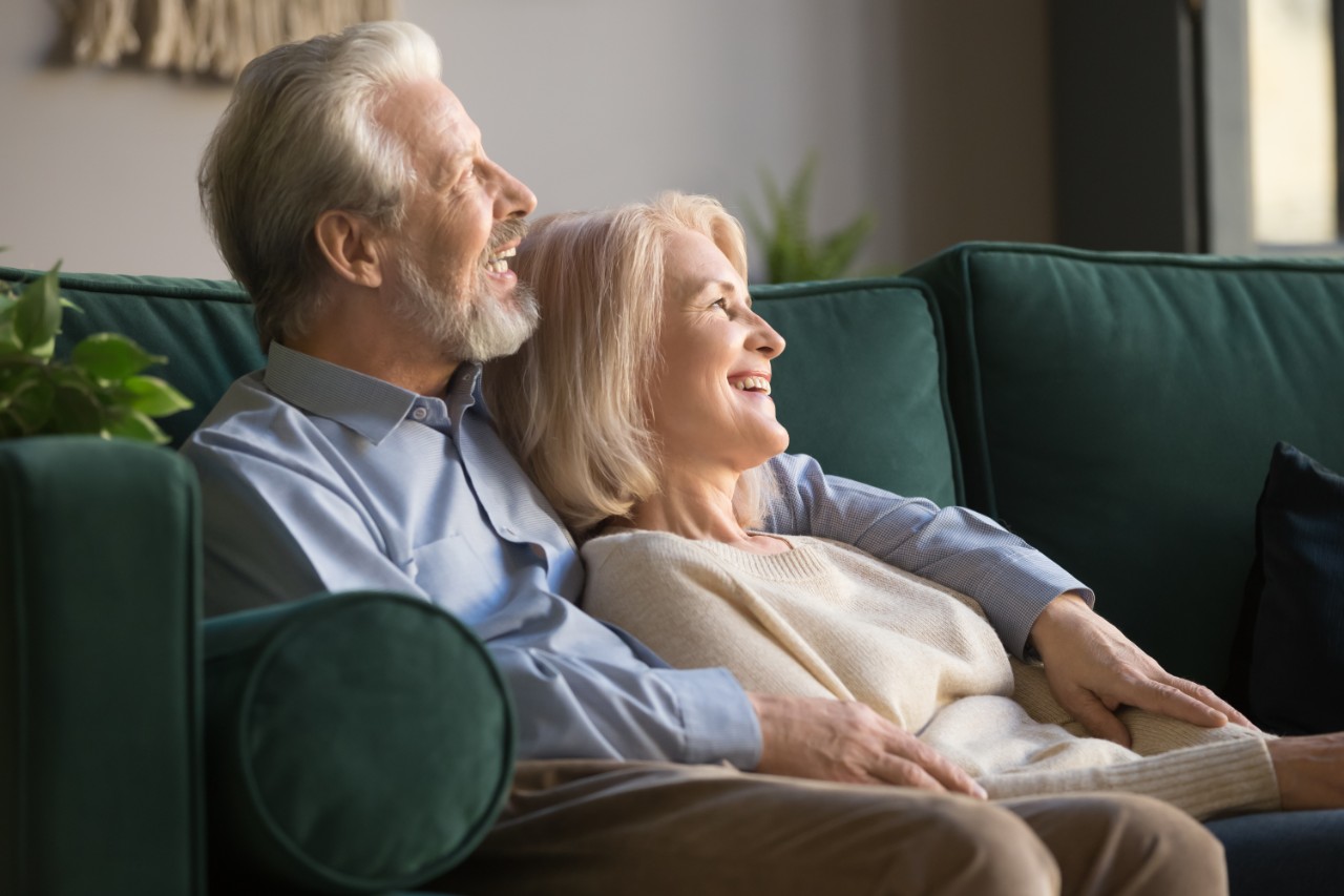 Elderly couple sitting on a sofa and smiling