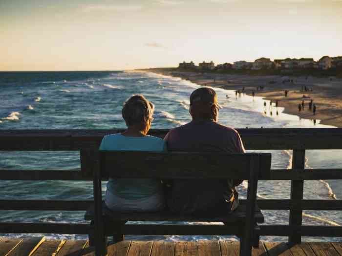 a couple sitting on a bench in front of the beach
