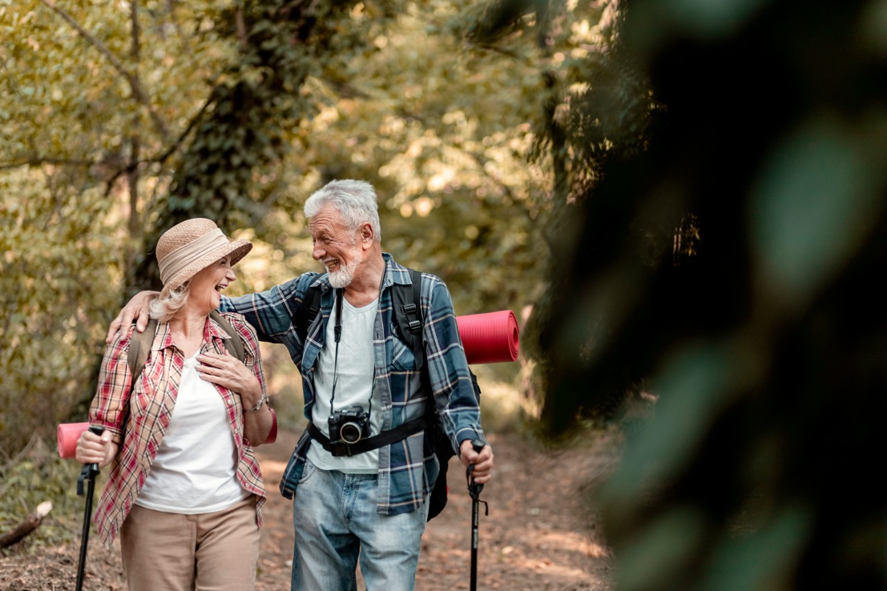 Old couple in the forest, smiling and laughing at each other