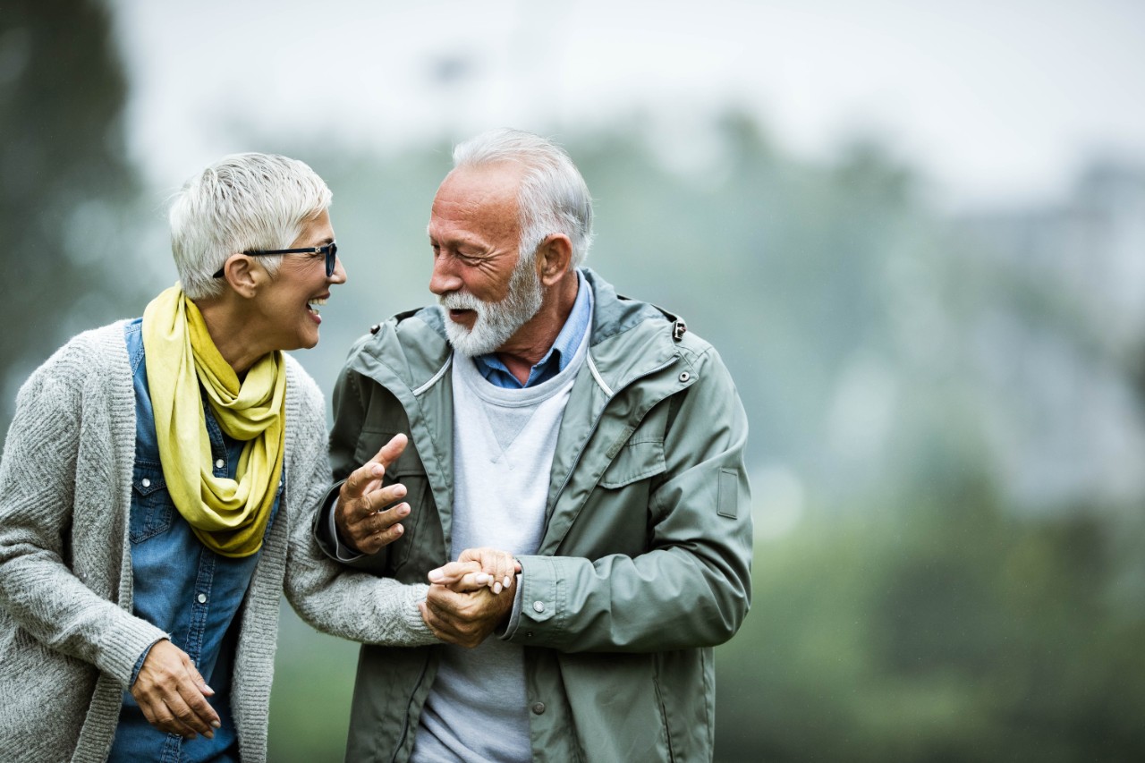 Old couple in the forest, smiling and laughing at each other