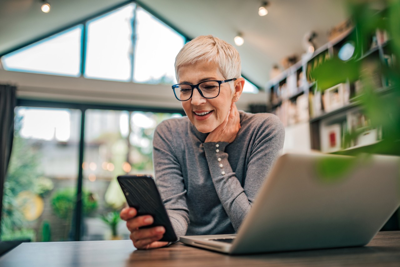 Old lady on her phone, smiling in her home office library