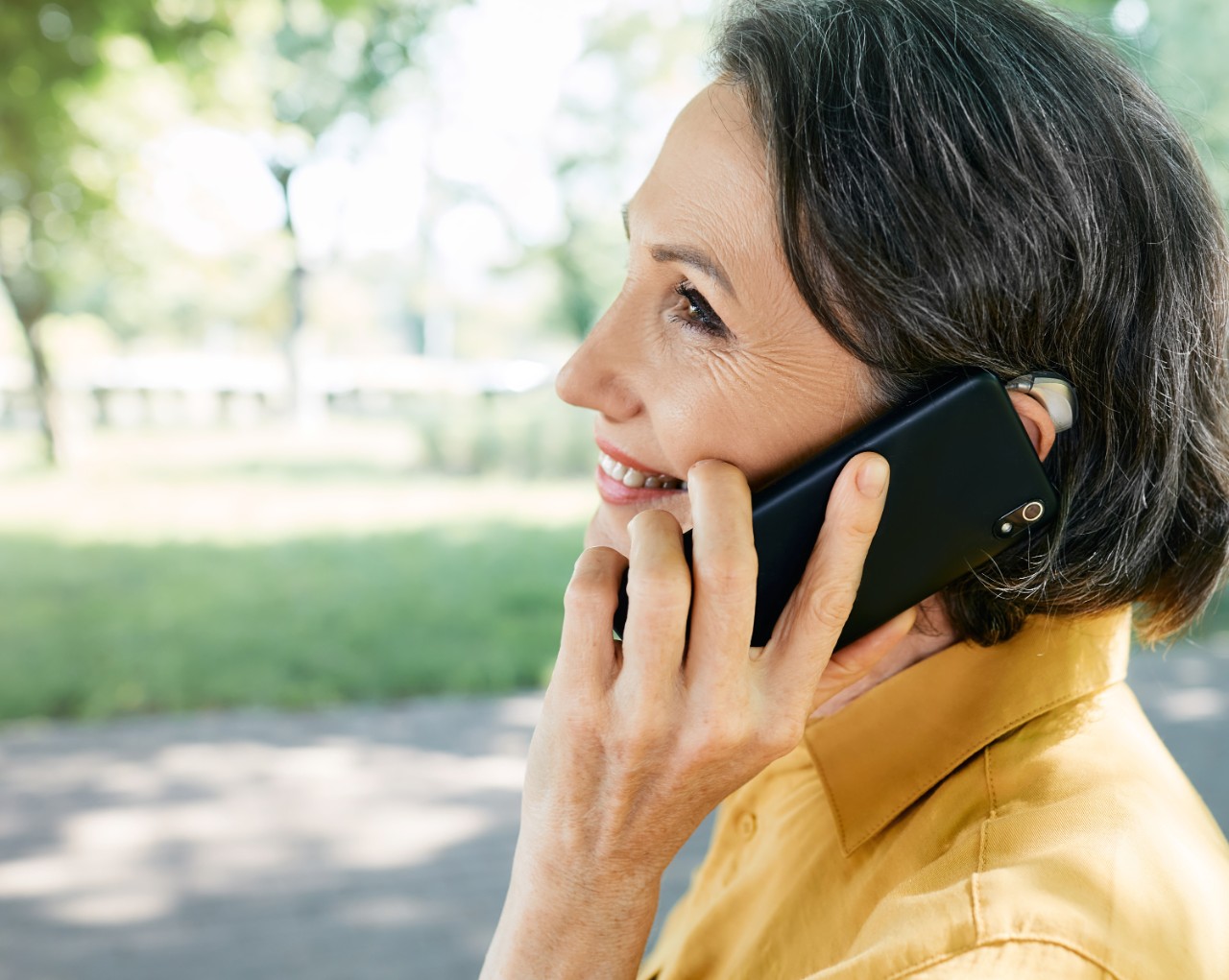 Woman holding her mobile phone while wearing a hearing aid