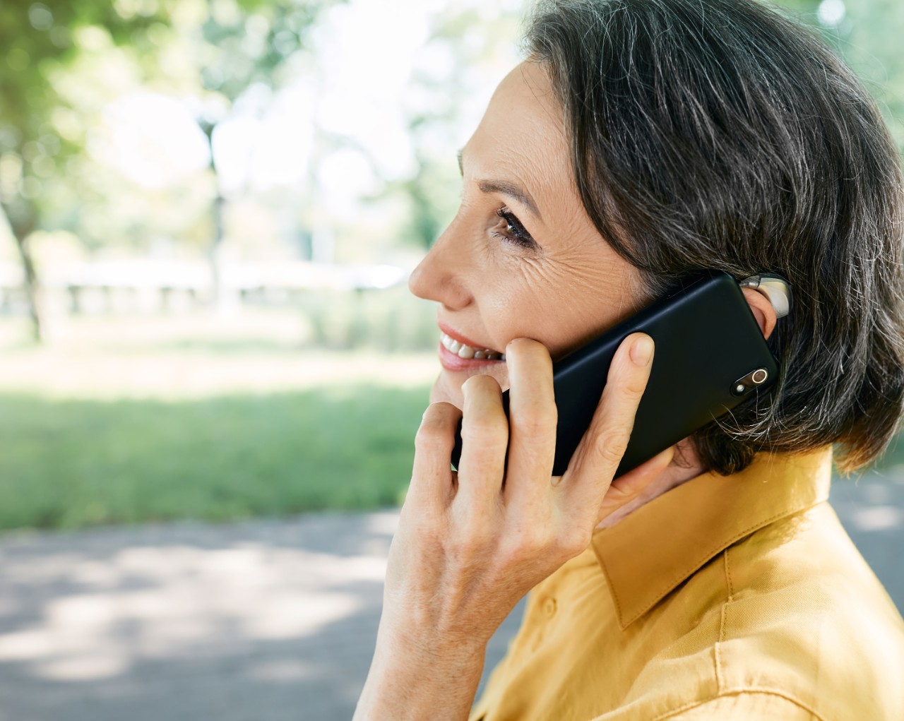 Femme tenant son téléphone portable tout en portant une prothèse auditive