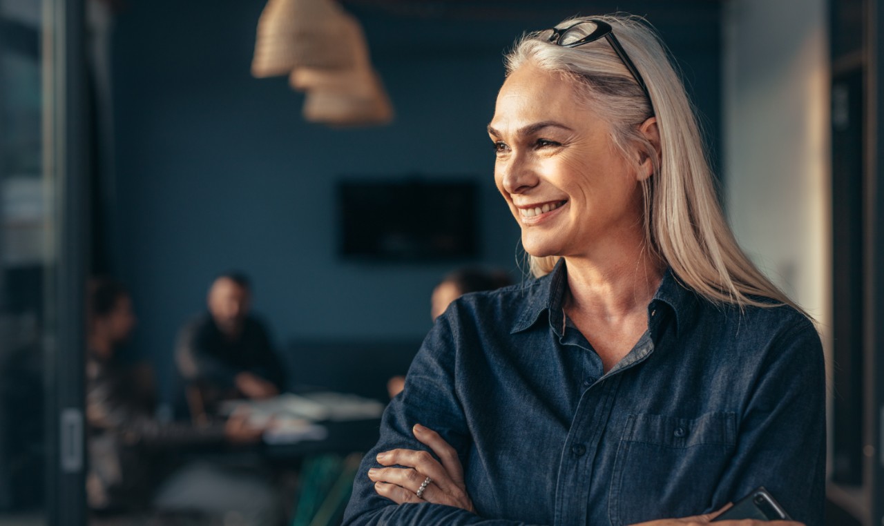 Femme souriante, avec quelques amis en arrière-plan à sa table