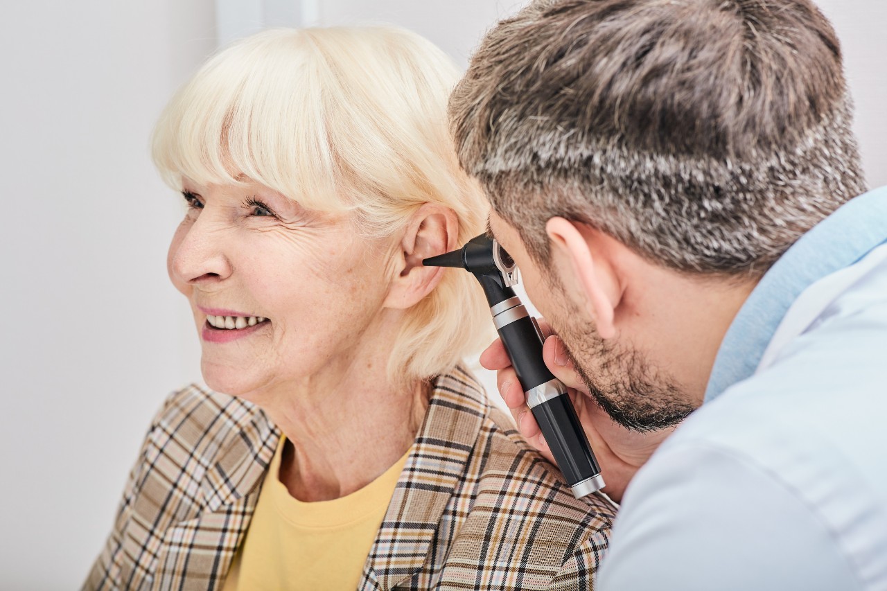 Médico que examina el nivel auditivo de una señora mayor