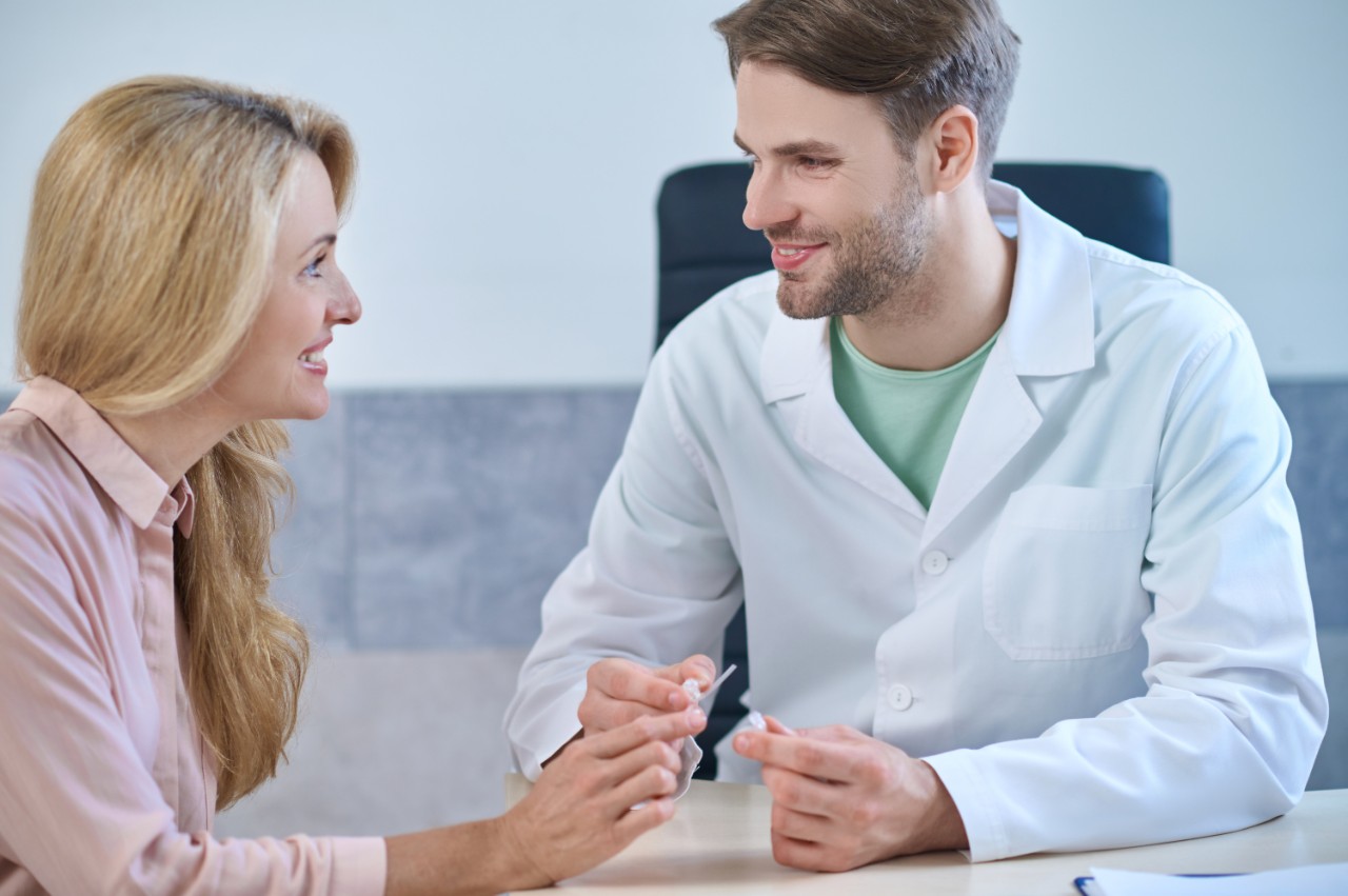 Doctor smiling at the patient, who is smiling back while holding the hearing aids