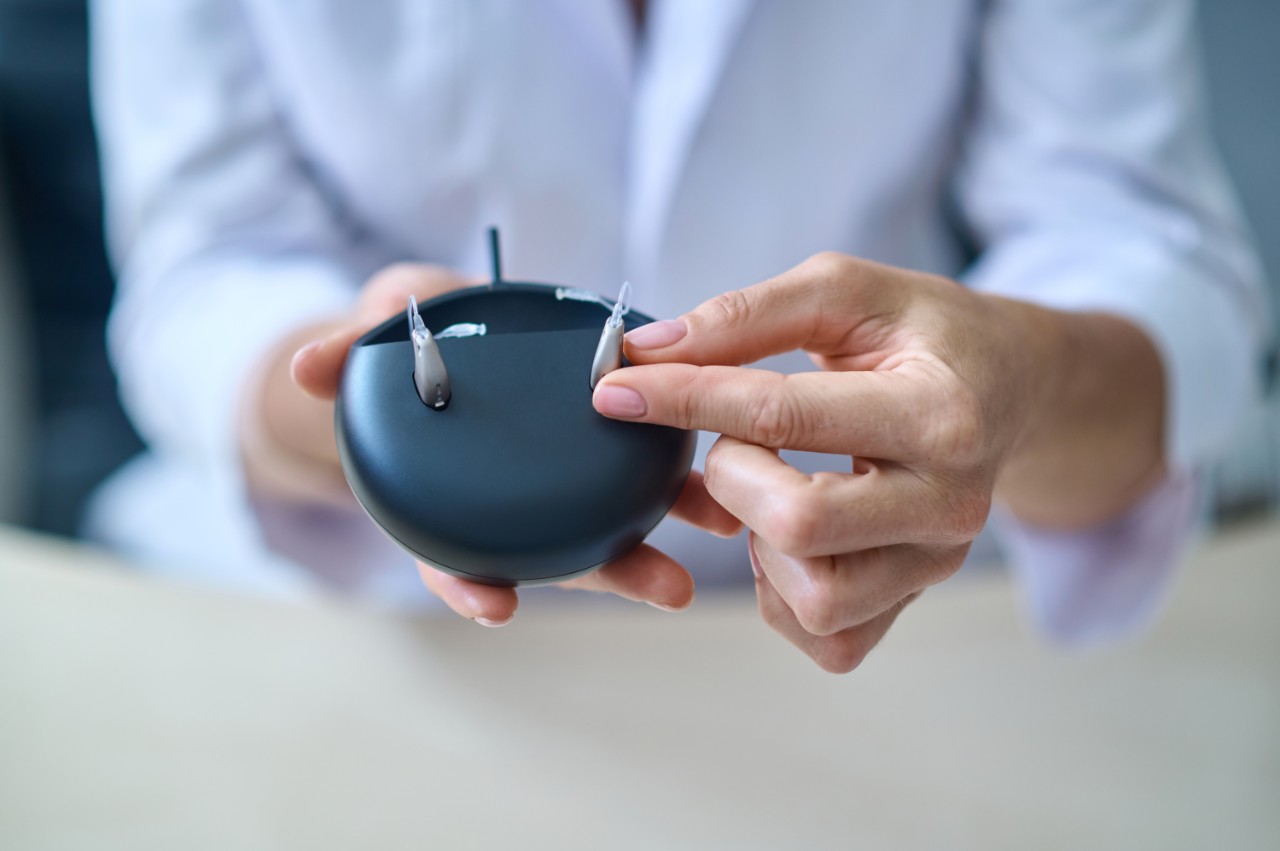 Doctor showing the hearing aids with the casing open