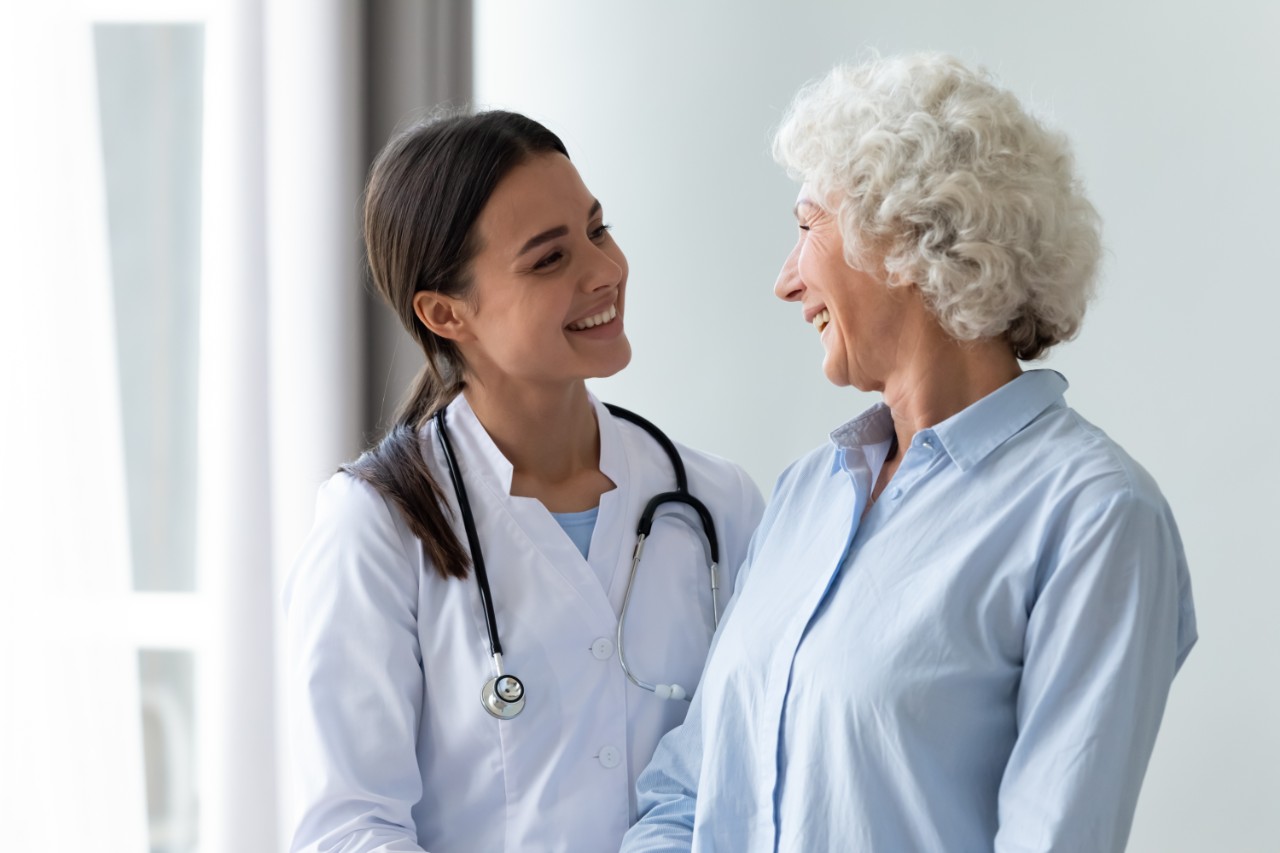 Young doctor smiling at an old lady, and the patient smiling back at her