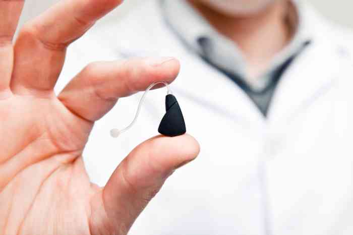 An audiologist holding a hearing aid in his hands