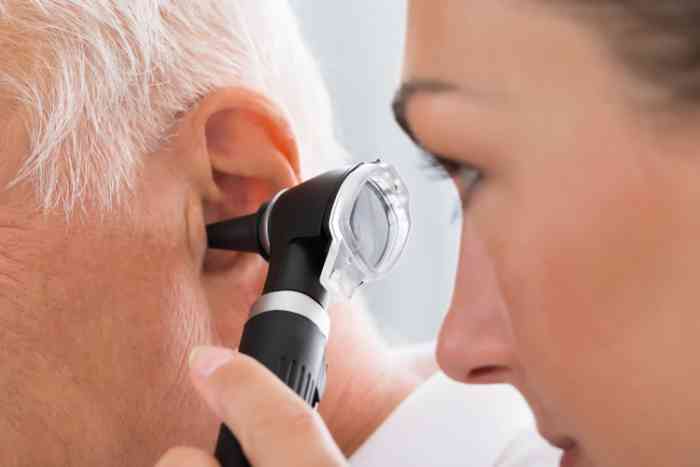 Una dottoressa controlla l'orecchio di un paziente con l'otoscopio