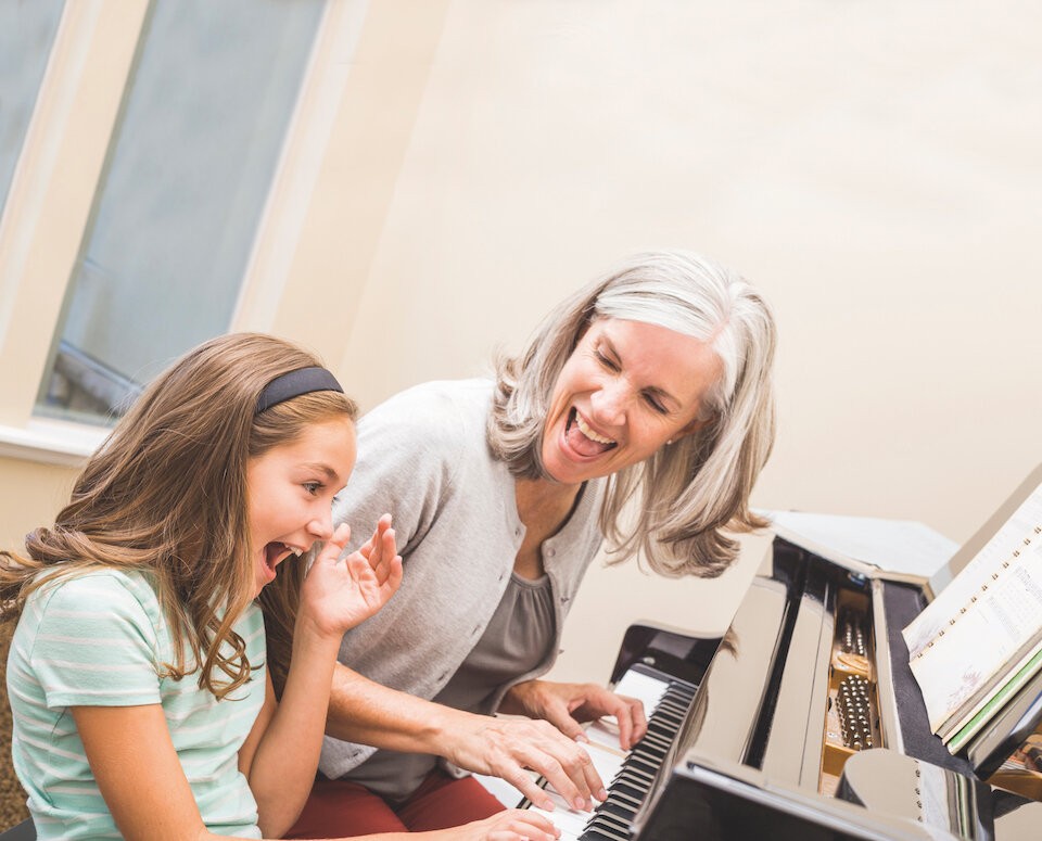 Grandmother playing piano with her granddaughter 